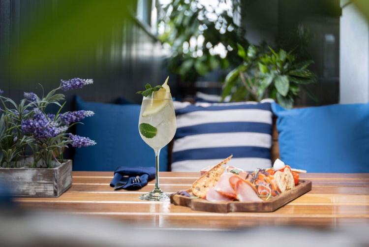 Hugo Spritz cocktail served at Harbour Hotel Galway, set on a wooden table with light bites and waterfront-style decor.